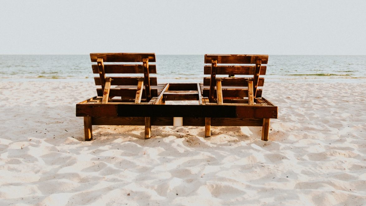 brown wooden chair on white sand beach during daytime